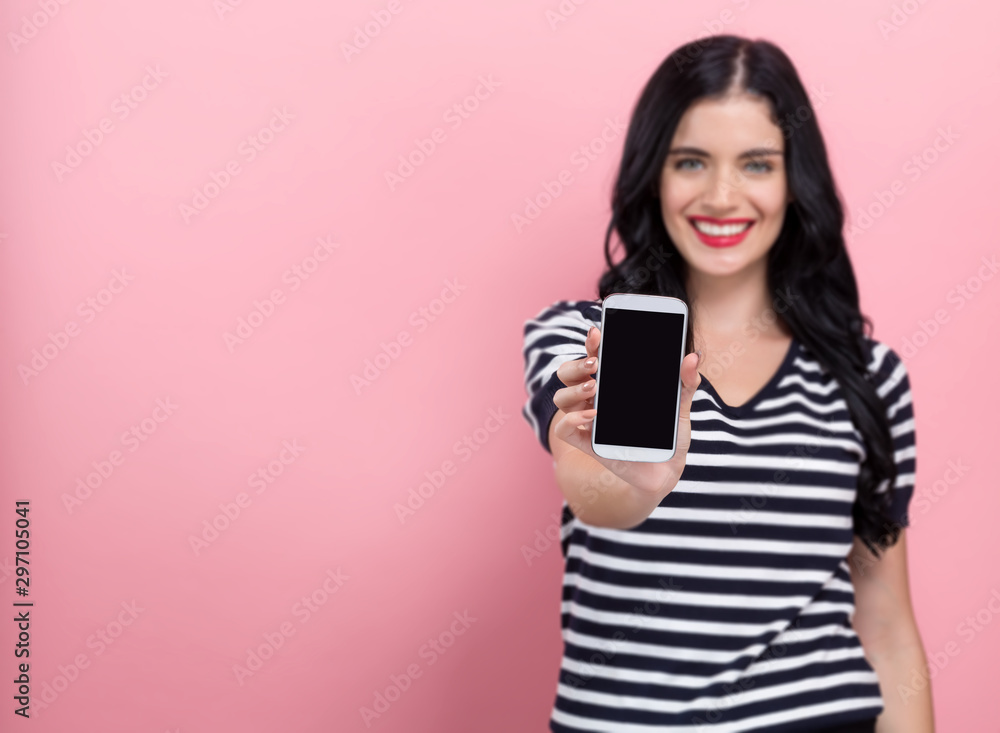 一位年轻女子在粉色背景下手里拿着一部手机