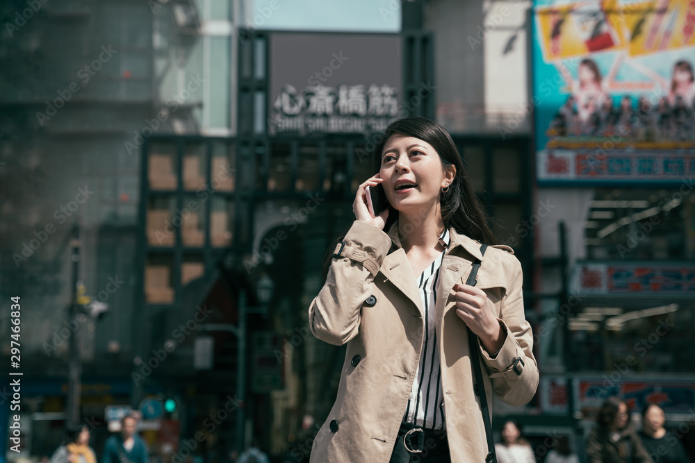 穿着外套的年轻城市女性在繁忙地区用手机行走和交谈的正视图