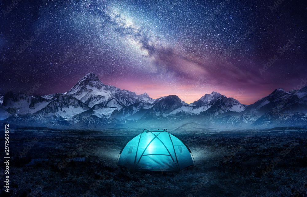 在星空下的山里露营。一个帐篷搭起来，在银河下闪闪发光。照片c