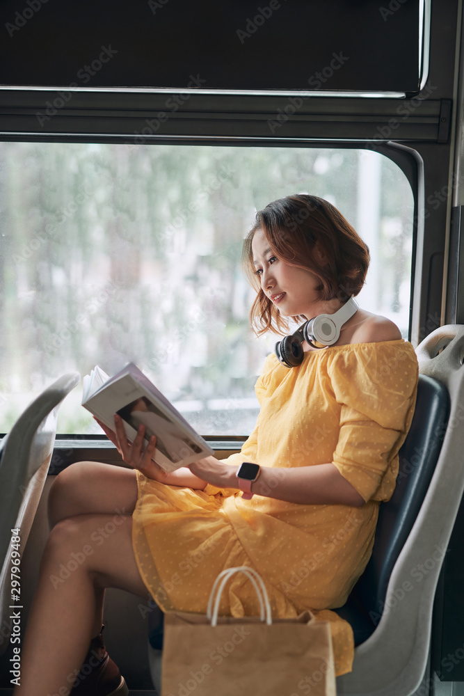 年轻女子在现代有轨电车上看书，公共交通工具上快乐的乘客