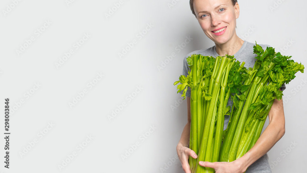 妇女手持绿色新鲜芹菜。健康饮食、素食、节食和以人为本