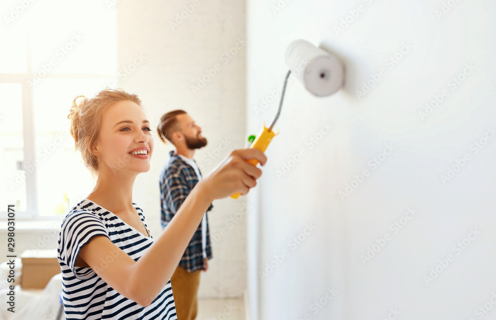 一对幸福的年轻夫妇正在家里修理和粉刷墙壁。