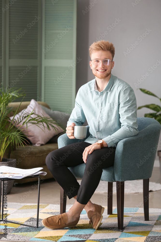 Portrait of stylish young man with cup of coffee resting at home