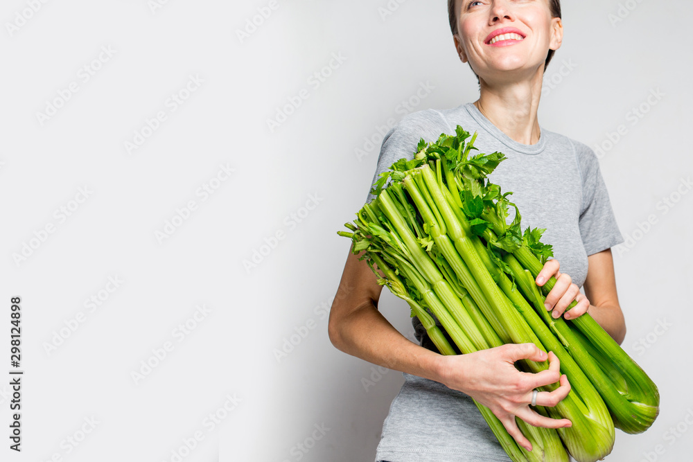 Woman holding green fresh celery. Healthy eating, vegetarian food, dieting and people concept