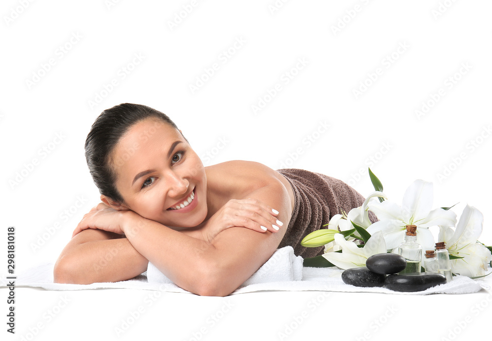 美丽的女人，带着水疗用品躺在白色背景下的毛巾上