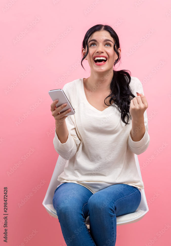 年轻女子在粉色背景下使用手机