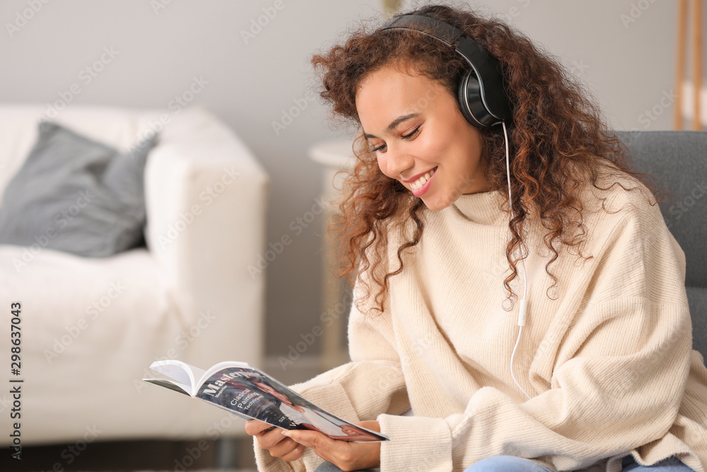 美丽的非裔美国女性在家听音乐时阅读杂志
