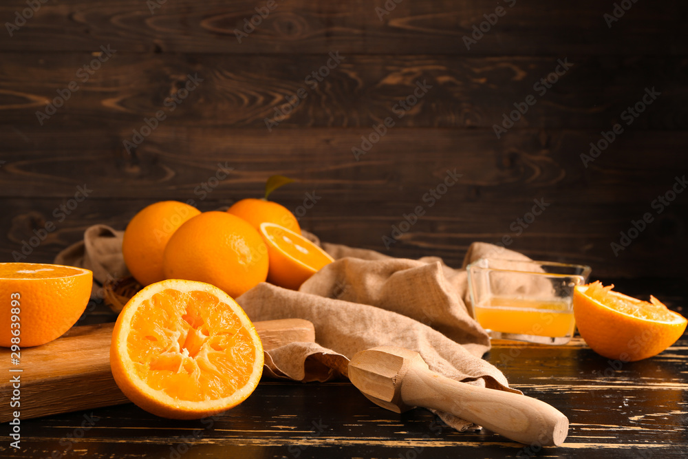 深色桌子上的新鲜橙子和果汁挤压机