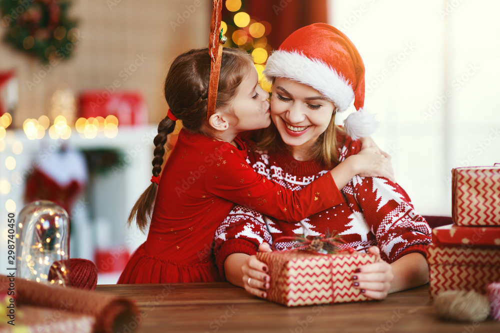 happy family mother and child pack Christmas gifts at home near Christmas tree