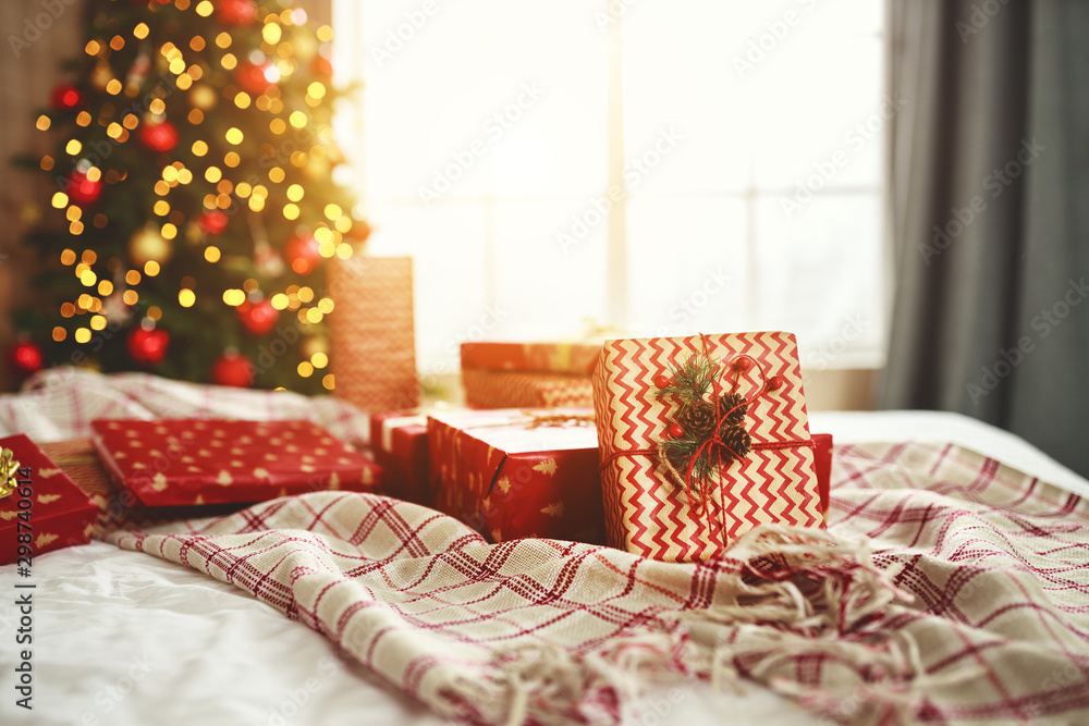 Christmas gifts on   bed near   Christmas tree in   morning in   bedroom  .