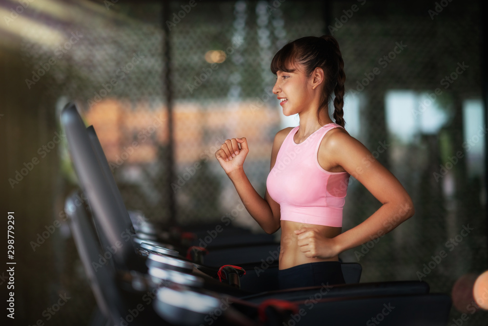 亚洲女孩在健身馆跑步器材