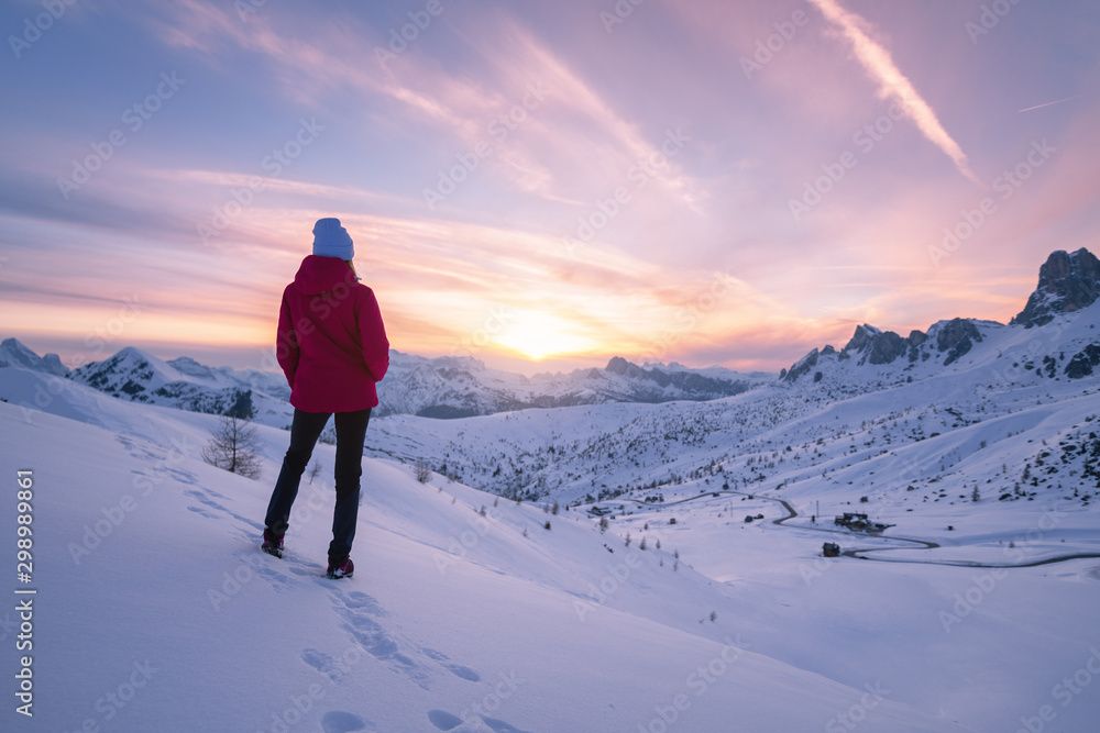 冬天日落时雪山中的年轻女子。山上有美丽苗条女孩的风景
