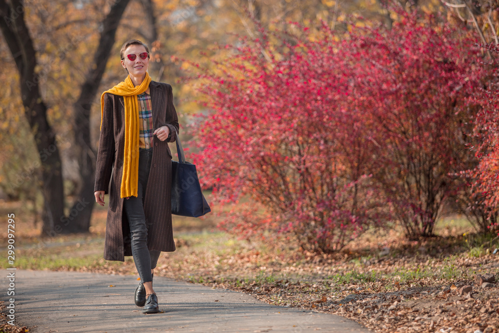 穿着时尚秋季服装的时尚秋季女性在秋季公园散步