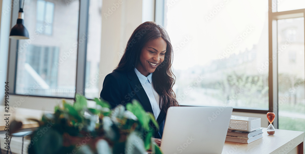 Smiling African American businesswoman using a laptop at her des