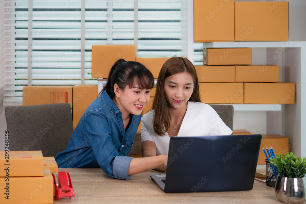 两名亚洲青少年老板女商人坐在桌子上进行网上购物，检查订单