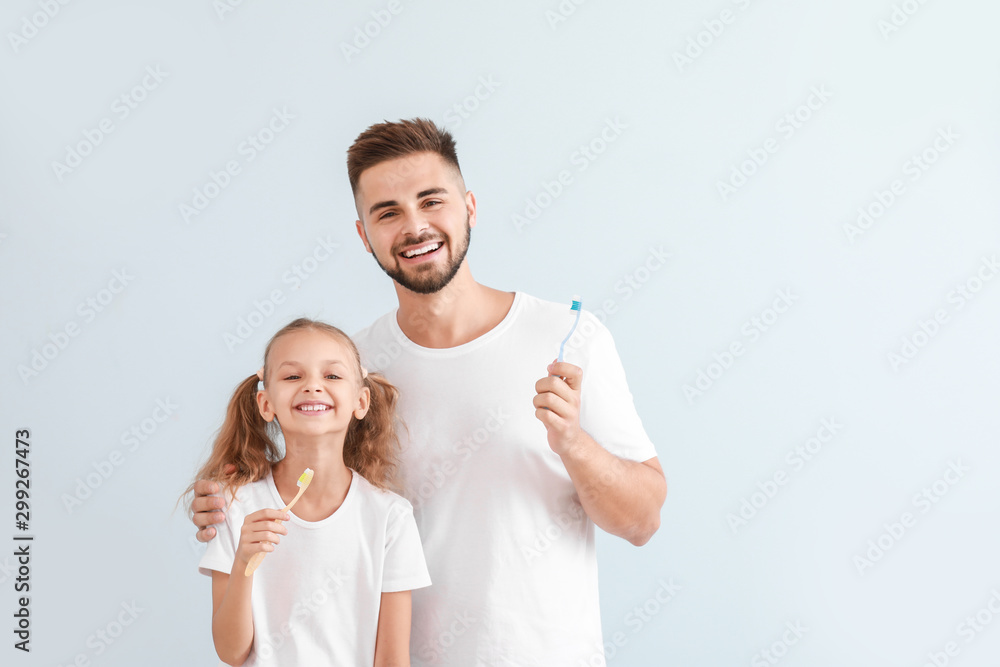父亲和他的小女儿在浅色背景下用牙刷的肖像