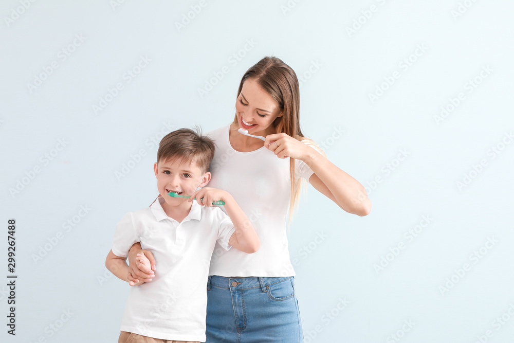 母亲和她的小儿子在浅色背景下刷牙的肖像