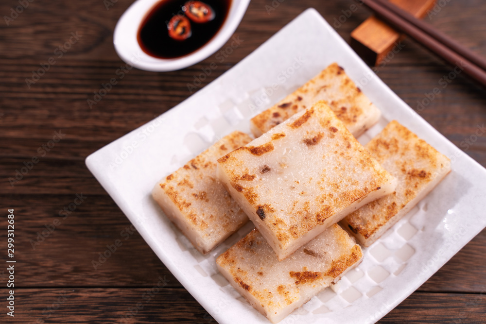 Delicious turnip cake, Chinese traditional local dish radish cake in restaurant with soy sauce and c