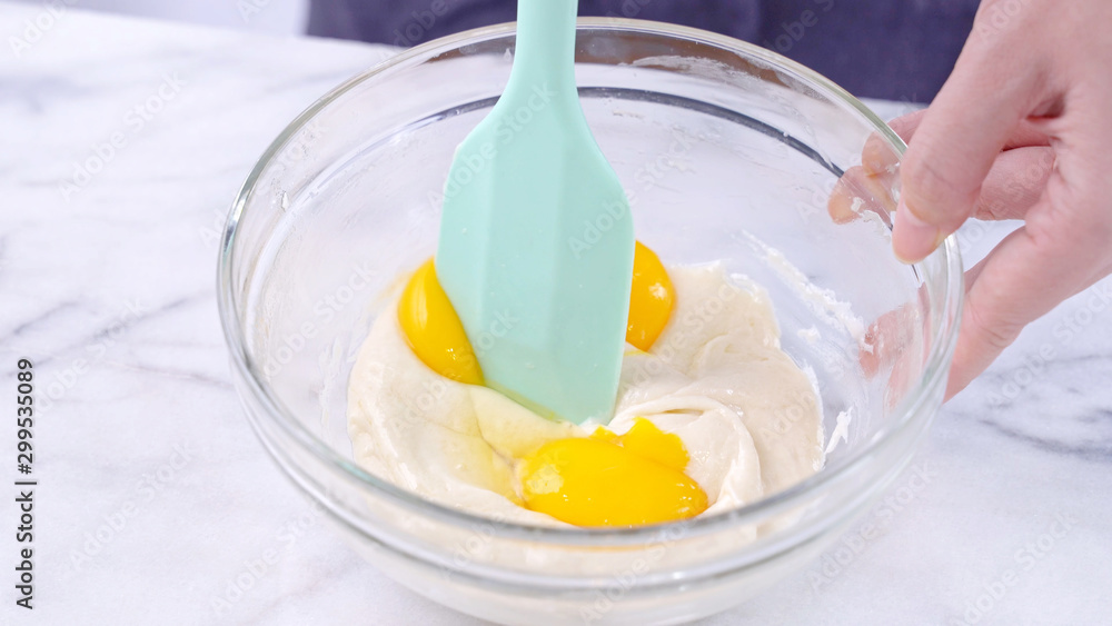 用绿色橡胶抹刀搅拌工具将蛋黄搅拌到蛋糕面糊中，搅拌至光滑起泡