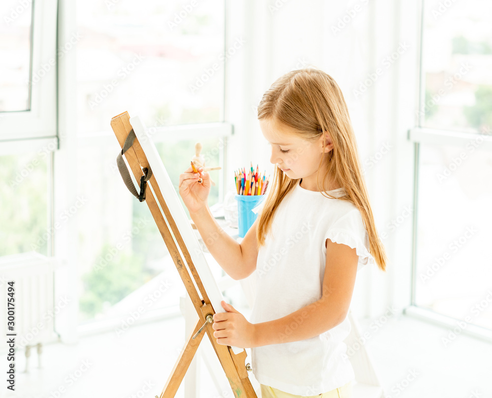 小女孩在画架上画不同的画