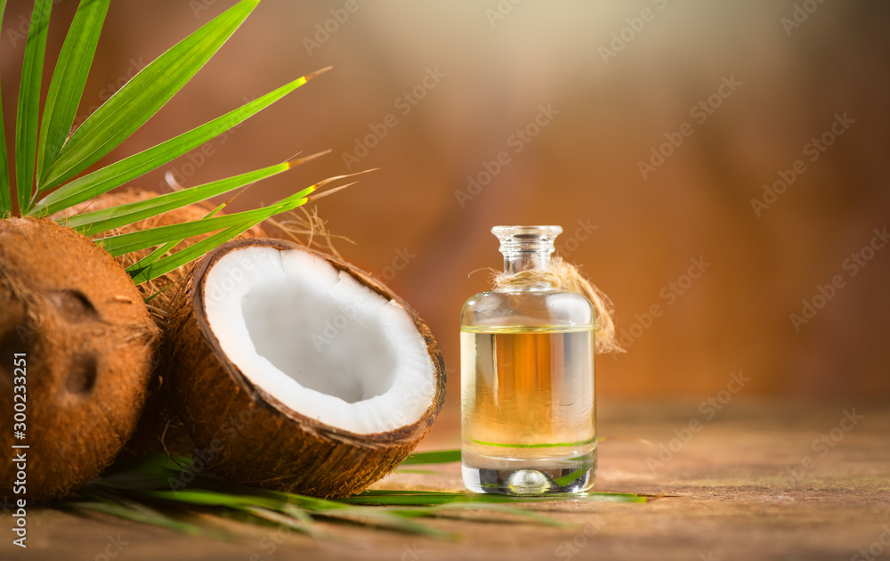 装在瓶子里的椰子棕榈油，棕色背景上有椰子和绿色棕榈树叶。椰子cl