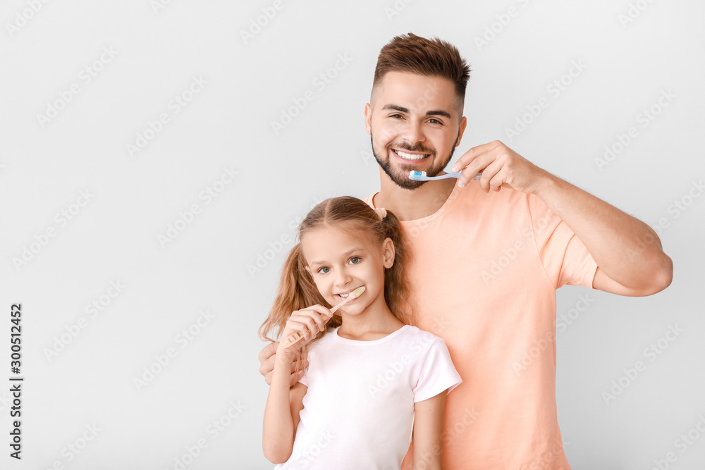 一名男子和他的小女儿在浅色背景下刷牙的肖像
