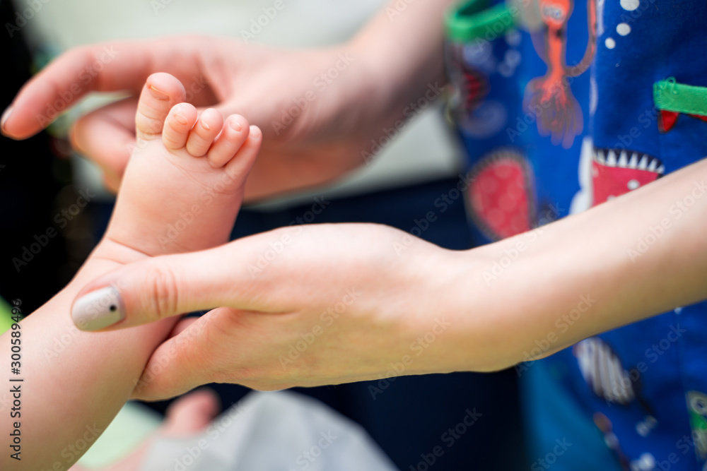 儿科医生在诊所检查小婴儿。医生手中孩子腿的特写。