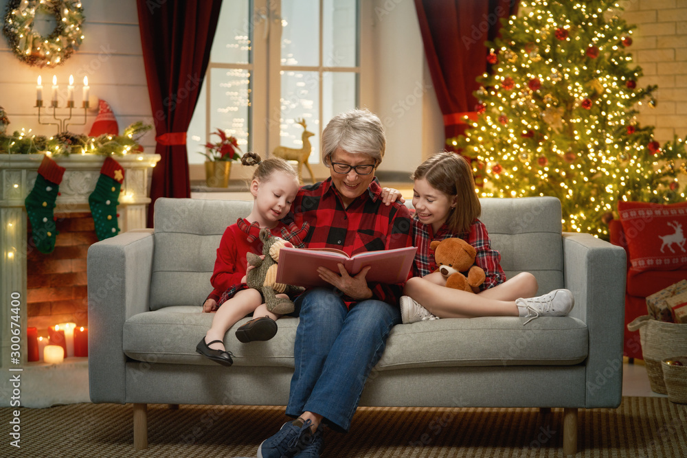 祖母在圣诞树旁给孙女们读书。