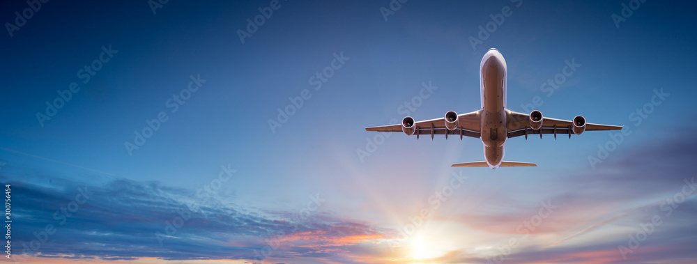 日落时，一架商用飞机在引人注目的云层上方飞行。