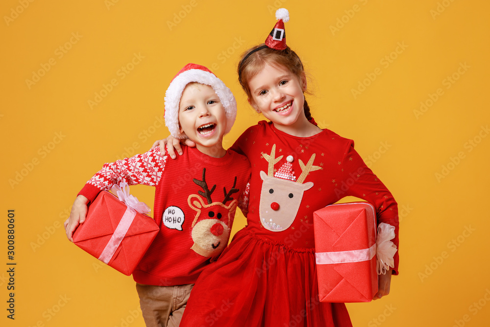 快乐有趣、情绪激动的孩子男孩和女孩穿着红色圣诞驯鹿服装，黄色礼物