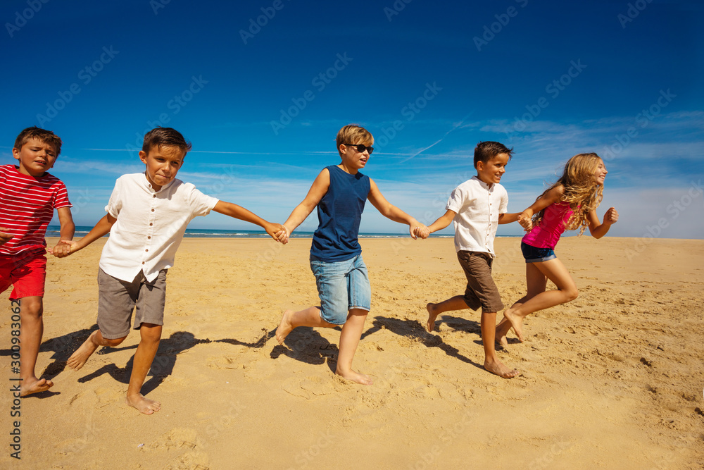 许多孩子手牵着手在沙滩上奔跑