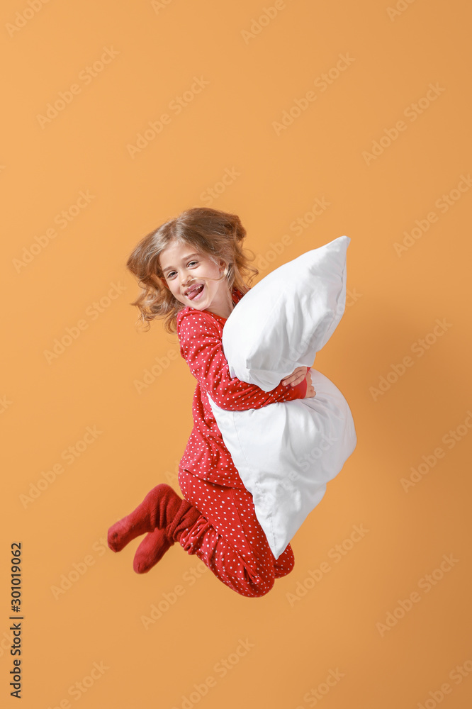 穿着睡衣、背景是枕头的跳跃小女孩