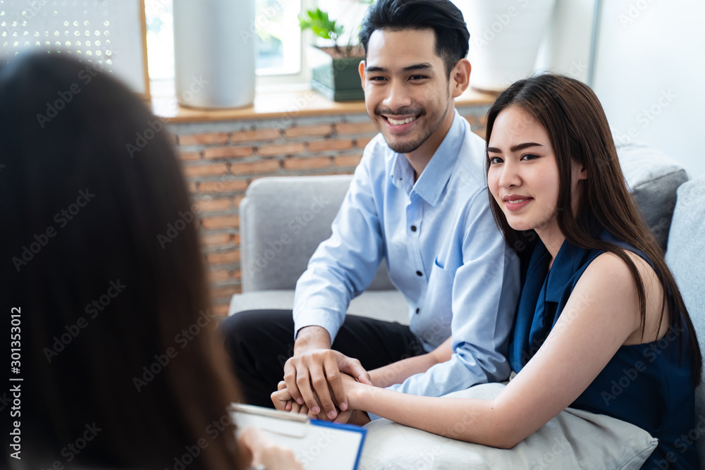 Asian couple patients sitting on sofa explaining and consulting problem to professional psychologist