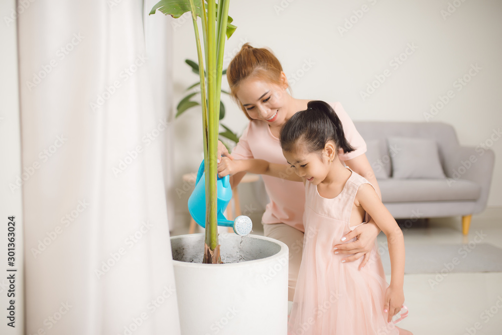 妈妈和女儿在公寓里给植物浇水