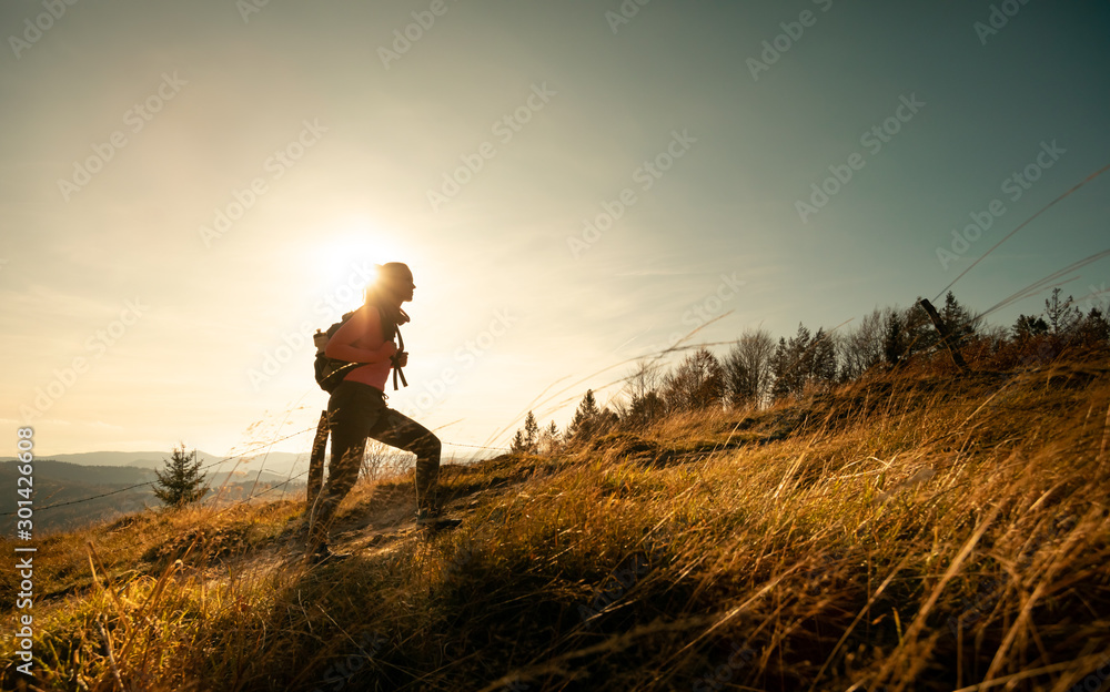 徒步旅行的年轻女子背着背包在群山景观背景下登上山顶