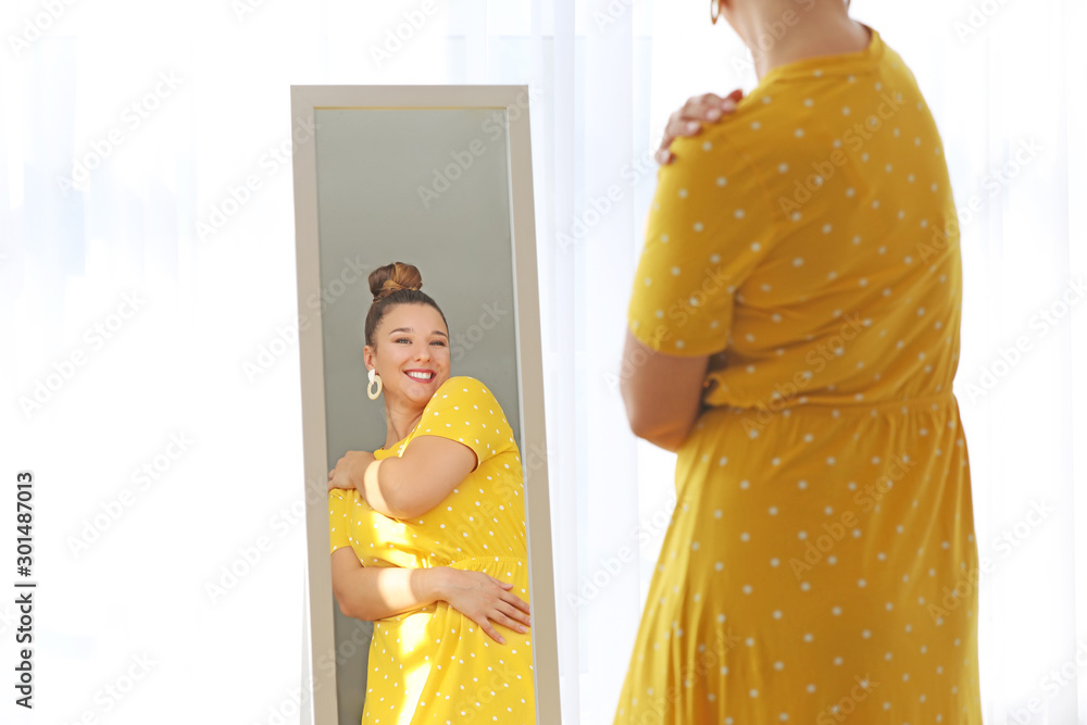 年轻的身体积极的女人在家照镜子