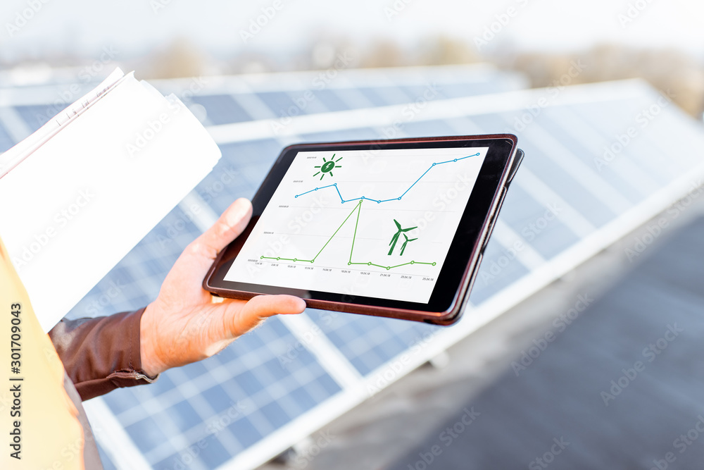 太阳能站上拿着数字平板电脑的男人，平板电脑屏幕上的特写，上面有太阳能和无线图表