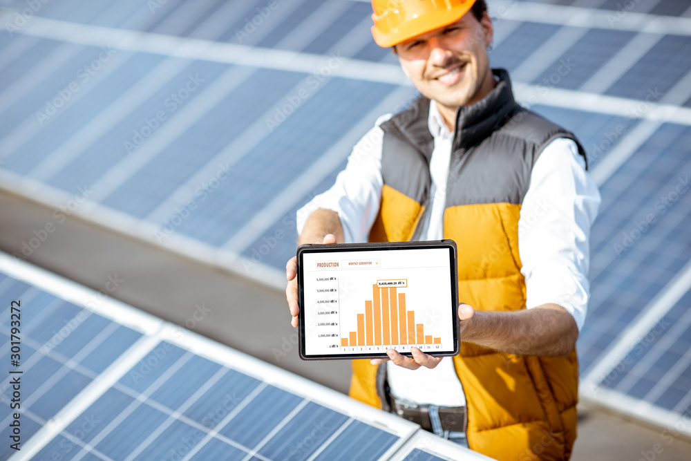 一名男子展示太阳能发电厂的发电情况，手里拿着一块有发电量图表的数字平板电脑