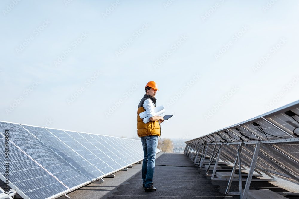 View on the rooftop solar power plant with mann walking and examining photovoltaic panels. Concept o