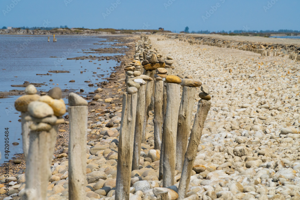 A row of wooden columns near the sea, the blue sky in the back