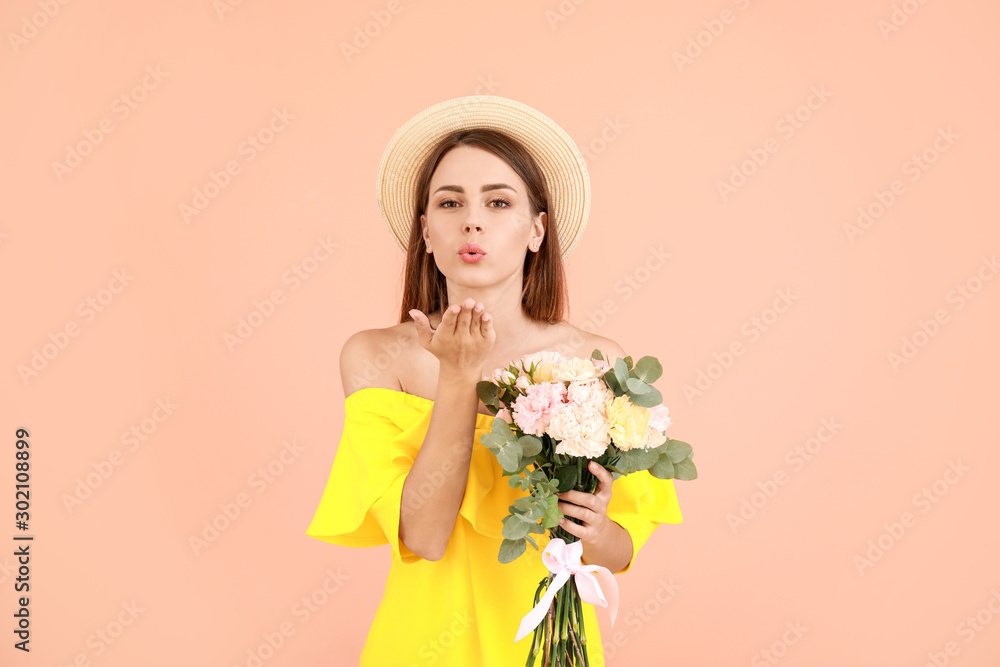 Beautiful young woman with bouquet of carnation flowers blowing kiss against color background