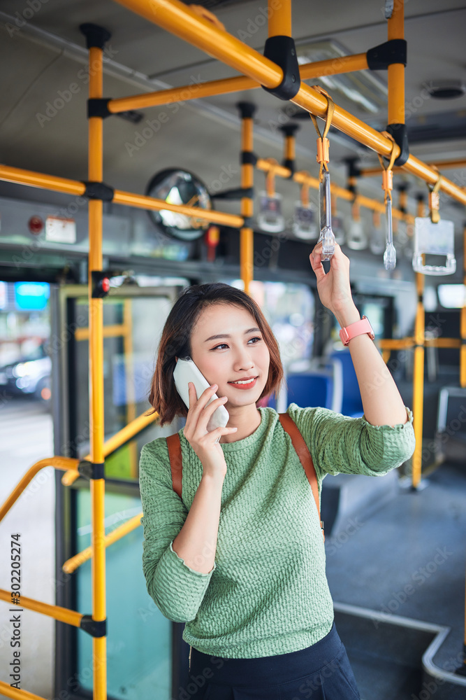 漂亮的女通勤者坐公交车上班时打手机
