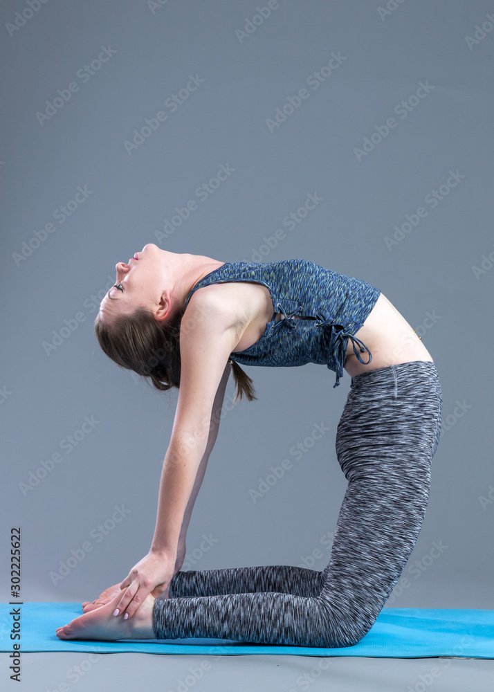 美丽、运动、健美的年轻女子练习瑜伽体式。