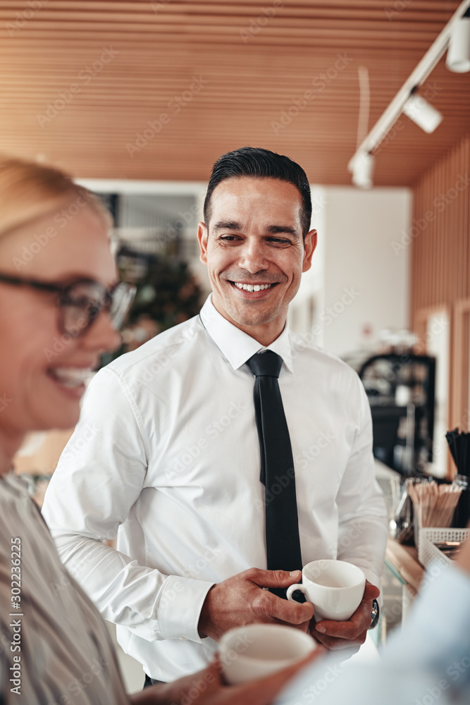 Smiling businessmen talking with coworkers over coffee in an off