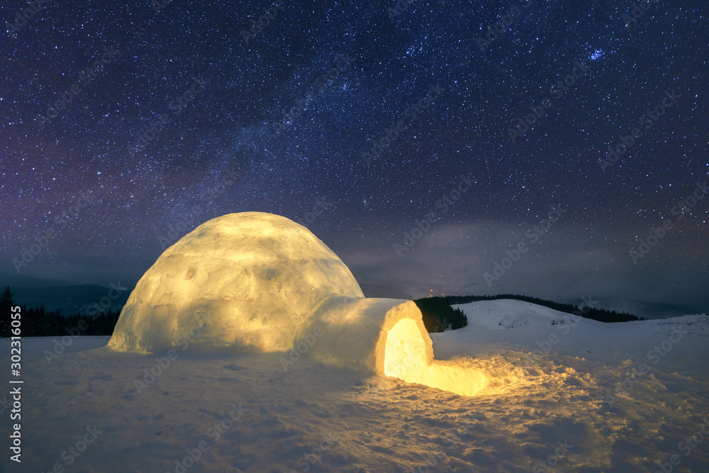 星光照耀下的奇妙冬季景观。夜晚有白雪皑皑的冰屋和乳白色的道路。