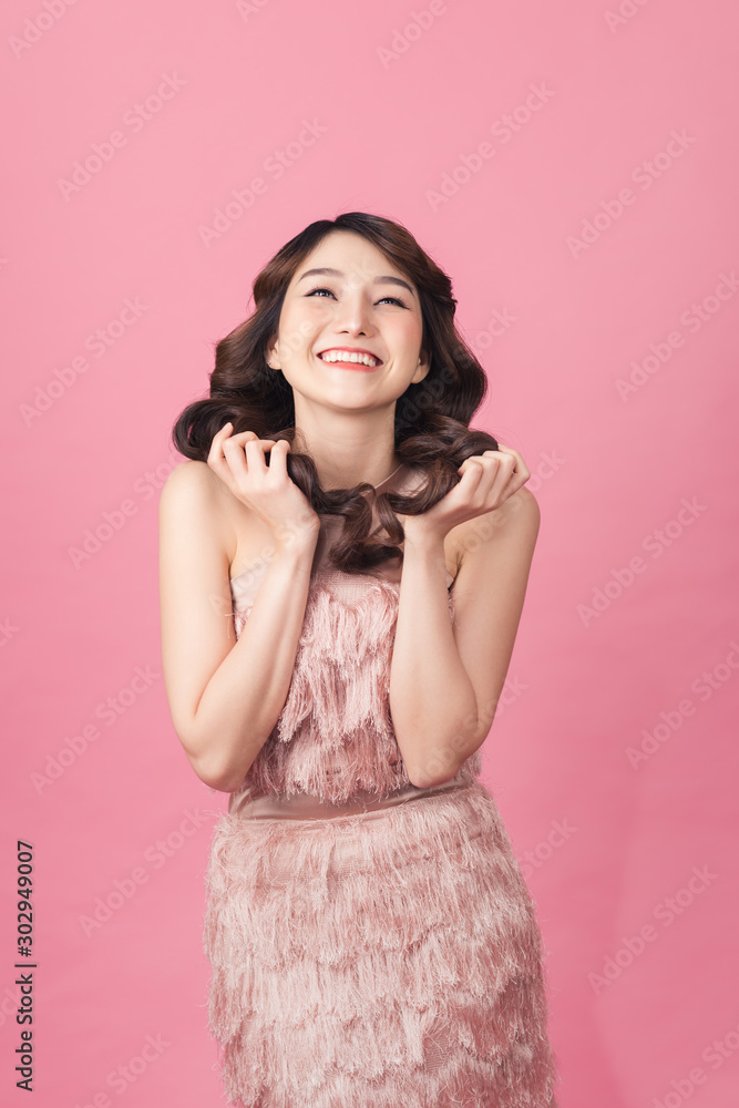 亚洲美女身穿粉色连衣裙。站在粉色背景前。
