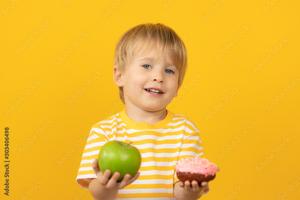 快乐的孩子拿着甜甜圈和苹果
