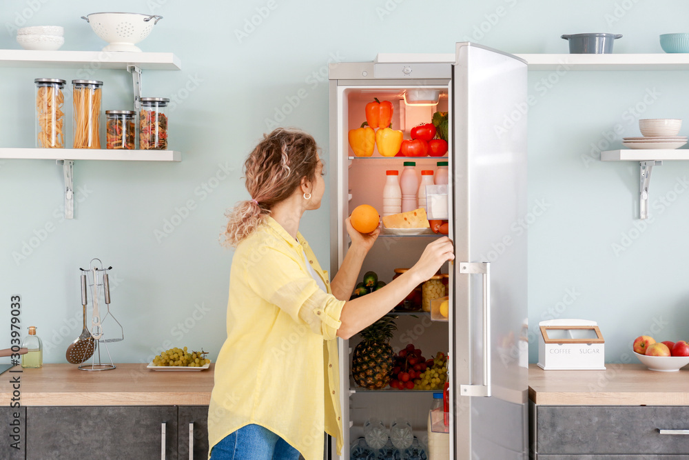 女人在家里用现代冰箱挑选食物