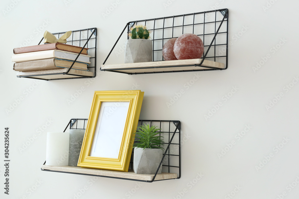 Shelves with decor hanging on light wall