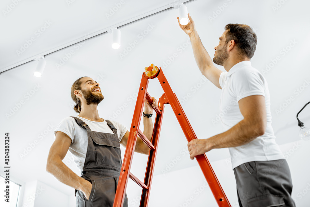 两名修理工或专业电工安装光点，站在客厅的梯子上